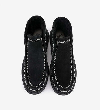 Black Aspen mocs by Pitas featuring water-resistant suede, faux-fur lining, and moccasin toe with white cross stitching.